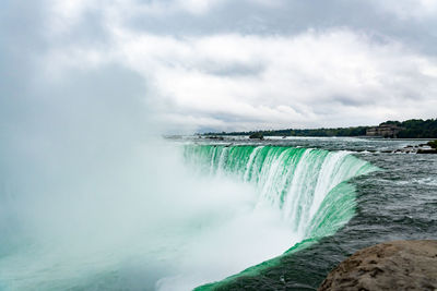 Scenic view of waterfall against sky