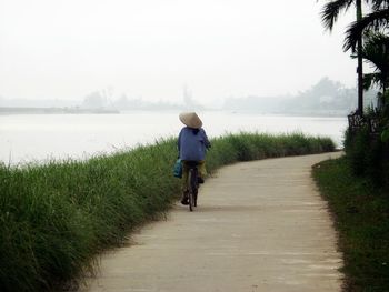 Rear view of man walking on field against sky