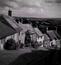 Houses by street on steep hill. cottages in village against sky