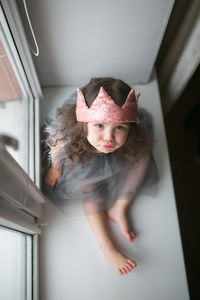 High angle portrait of cute girl sitting by window