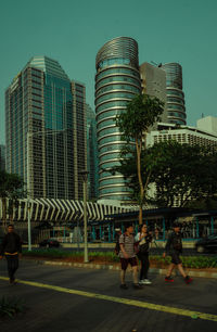 People in modern building against sky in city