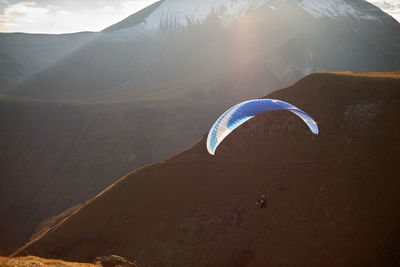 Paraglide silhouette over mountain peaks