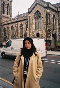 Portrait of young woman standing on street in city