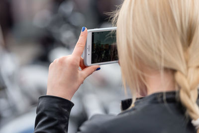 Rear view of woman photographing through mobile phone