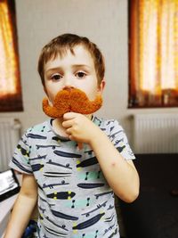 Portrait of boy holding camera at home