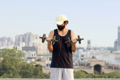 Man wearing hat standing against cityscape