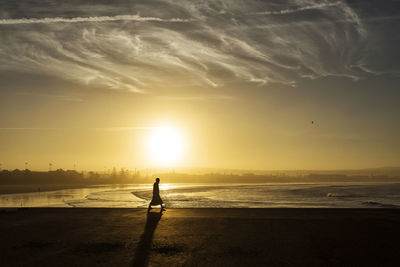 Silhouette man on beach against sky during sunset