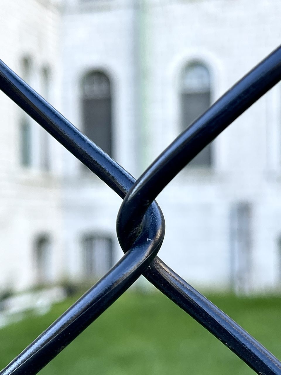 CLOSE-UP OF CHAIN ON METAL FENCE BY BUILDING