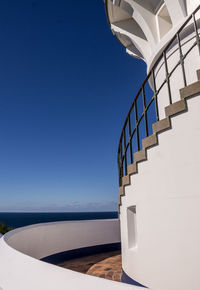 Staircase by sea against clear blue sky