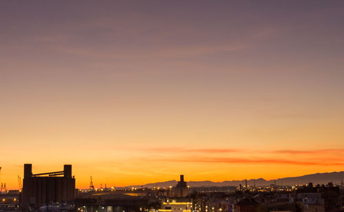 Illuminated buildings against sky during sunset