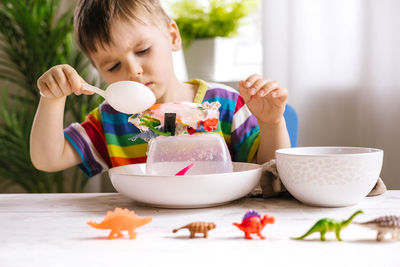 Boy playing with paint while holding spoon at home