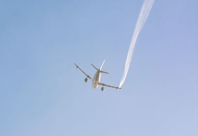 Low angle view of airplane flying against clear blue sky