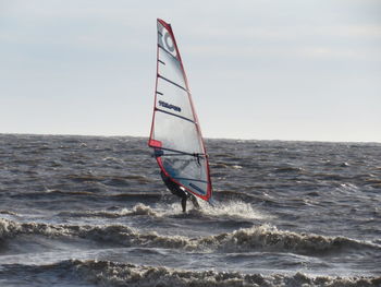 Person standing in sea against sky