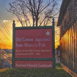 Information sign on field against sky at sunset