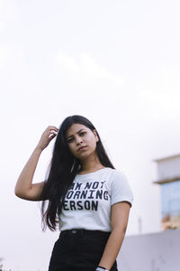 Beautiful young woman standing against white background