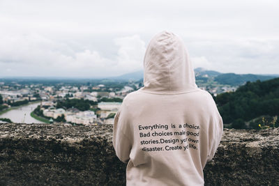 Rear view of man standing against sky in city