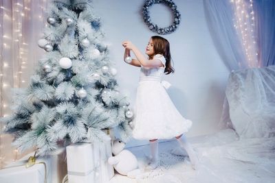 Full length of girl decorating christmas tree at home
