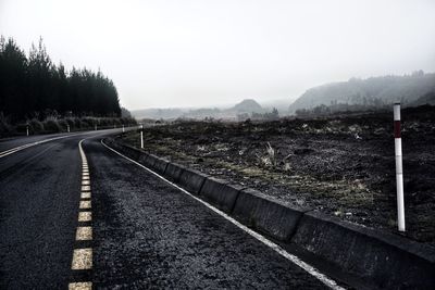 Empty road along landscape against sky