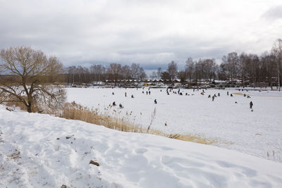 Snow covered field by trees against sky