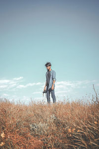 Young man standing on field against sky