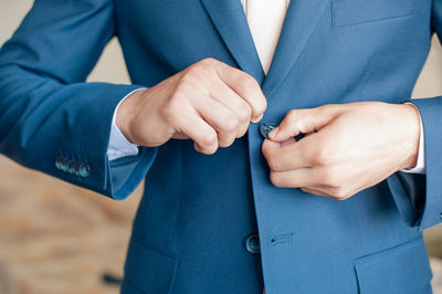 Midsection of man buttoning suit