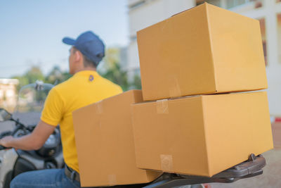 Rear view of delivery man riding with parcels on scooter