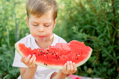 Boy eating watermelon white t-shirt. picnic with watermelons. 