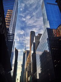 Low angle view of modern buildings against cloudy sky