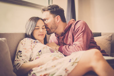 Man whispering in ear of pregnant woman at home