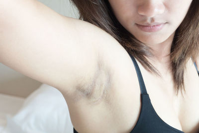 Close-up of woman showing armpit in bedroom at home