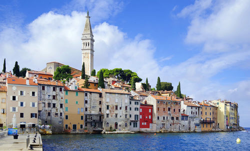 Buildings by canal against sky in city