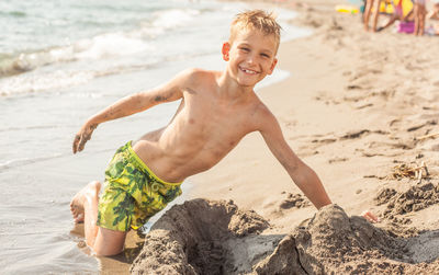 Shirtless boy playing on shore at beach during summer
