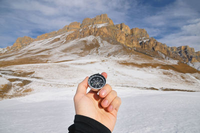 Midsection of person holding ice against mountain