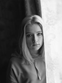 Portrait of beautiful young woman by curtain