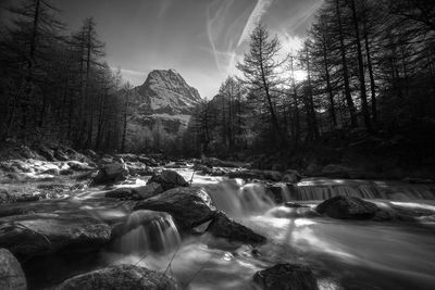 Scenic view of waterfall in forest against sky