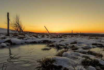 Scenic view of snow covered land during sunset