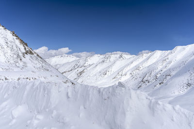 Scenic view of snowcapped mountains against blue sky