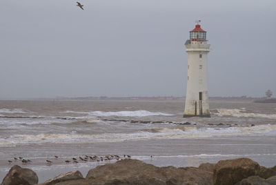 Lighthouse by sea against sky