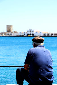 Rear view of man looking at sea against sky