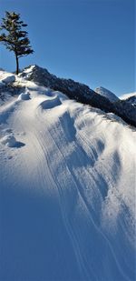 Scenic view of snow covered mountains against clear blue sky