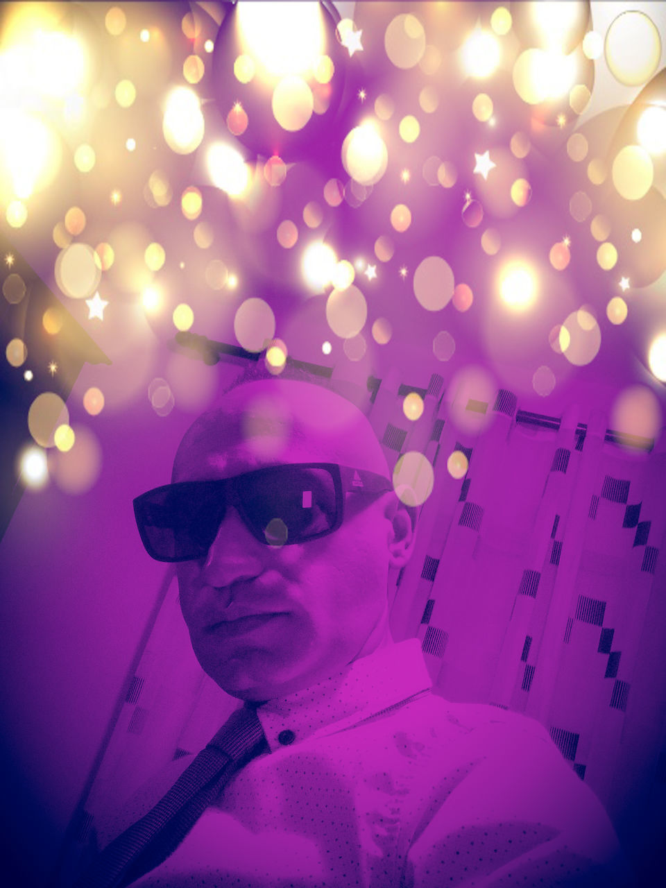 PORTRAIT OF YOUNG MAN WEARING SUNGLASSES AGAINST ILLUMINATED LIGHT