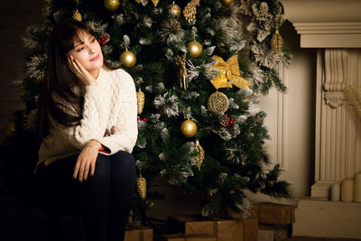 Young woman with christmas tree at home