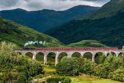 Train on arch bridge against mountains