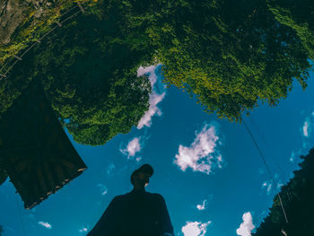 Low angle view of silhouette man standing by tree against sky
