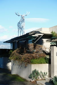 Statue amidst trees and building against sky