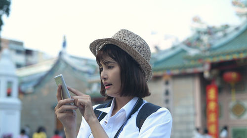 Portrait of woman holding hat against blurred background