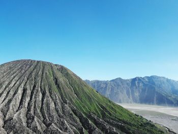 Panoramic view of volcanic mountain against clear blue sky