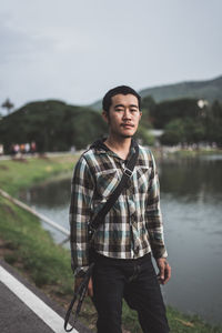 Portrait of young man standing against lake