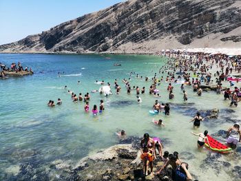 Group of people swimming in sea by mountain