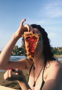 Portrait of woman holding sunglasses against sky